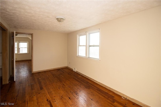 unfurnished room with a textured ceiling and dark wood-type flooring