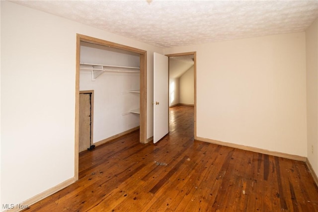 unfurnished bedroom with a textured ceiling, a closet, and dark hardwood / wood-style floors