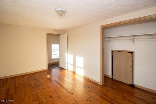 unfurnished bedroom with a textured ceiling, dark wood-type flooring, and a closet