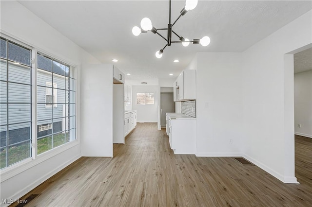 unfurnished living room with a notable chandelier and light hardwood / wood-style flooring