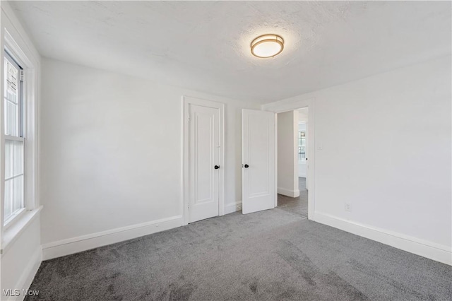 unfurnished room with carpet, a textured ceiling, and plenty of natural light