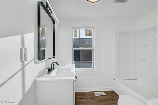 full bathroom with washtub / shower combination, wood-type flooring, vanity, and toilet