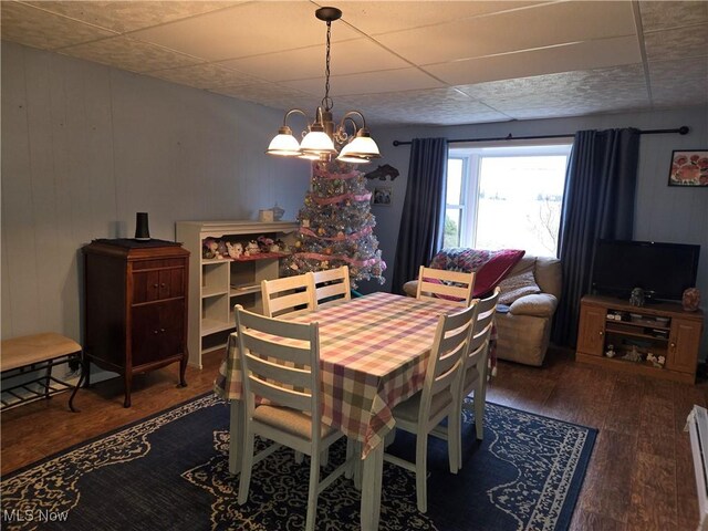 dining room with a notable chandelier, dark hardwood / wood-style floors, and wood walls