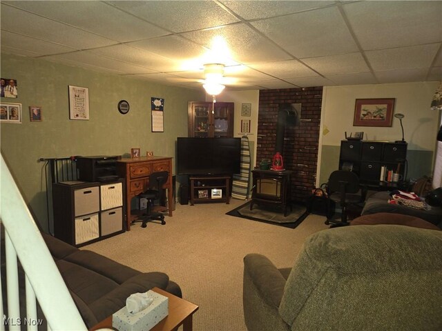 carpeted living room featuring a drop ceiling and a wood stove