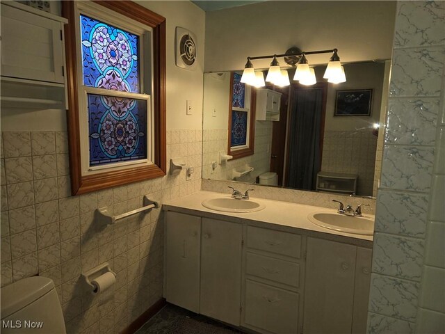 bathroom featuring vanity, tile walls, and toilet