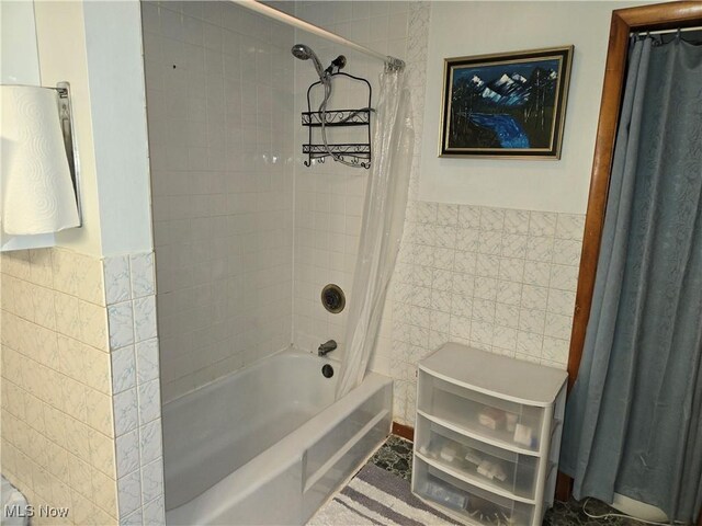 bathroom with shower / bathtub combination with curtain and tile walls