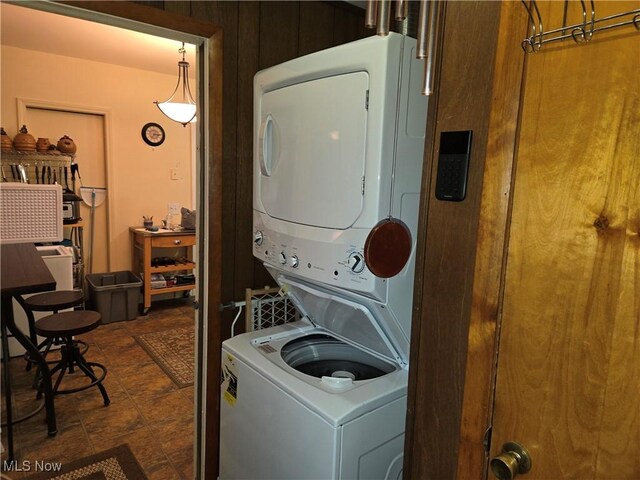 laundry room featuring wood walls and stacked washer and dryer