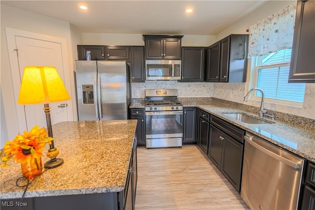 kitchen with light stone counters, sink, and stainless steel appliances