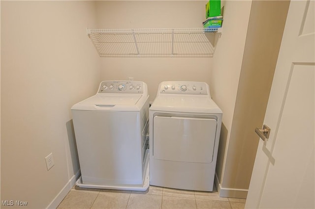 laundry area with washing machine and dryer and light tile patterned floors