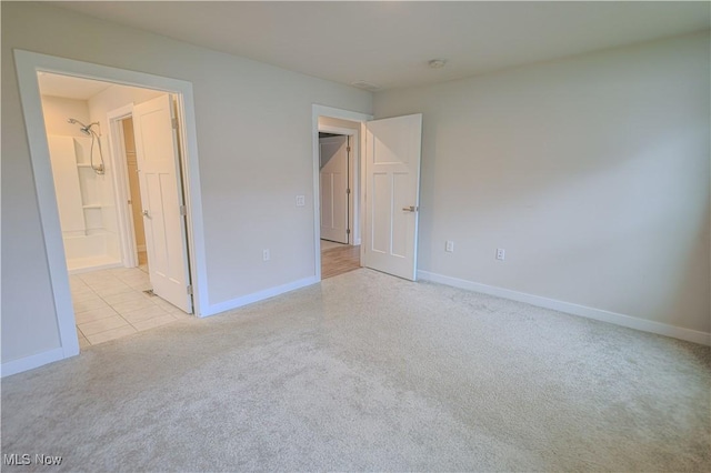 unfurnished bedroom featuring light carpet and ensuite bathroom