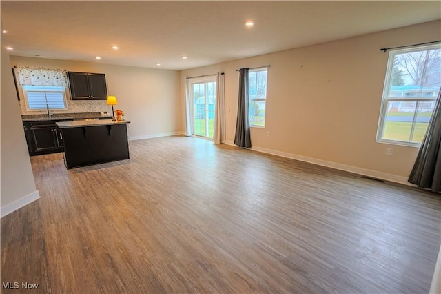 unfurnished living room with light hardwood / wood-style flooring, plenty of natural light, and sink