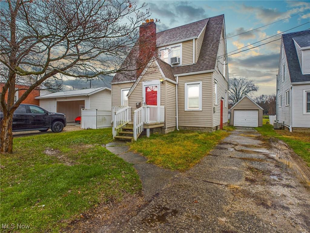 view of front of property featuring an outbuilding, a garage, cooling unit, and a front yard