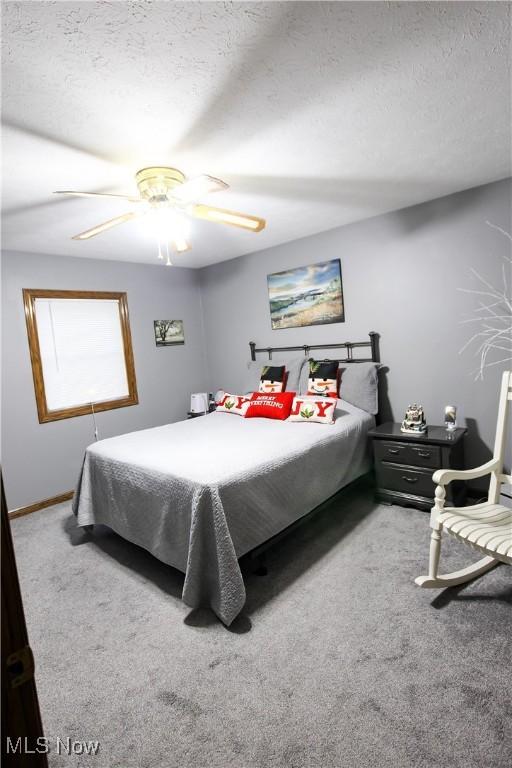 carpeted bedroom featuring ceiling fan and a textured ceiling