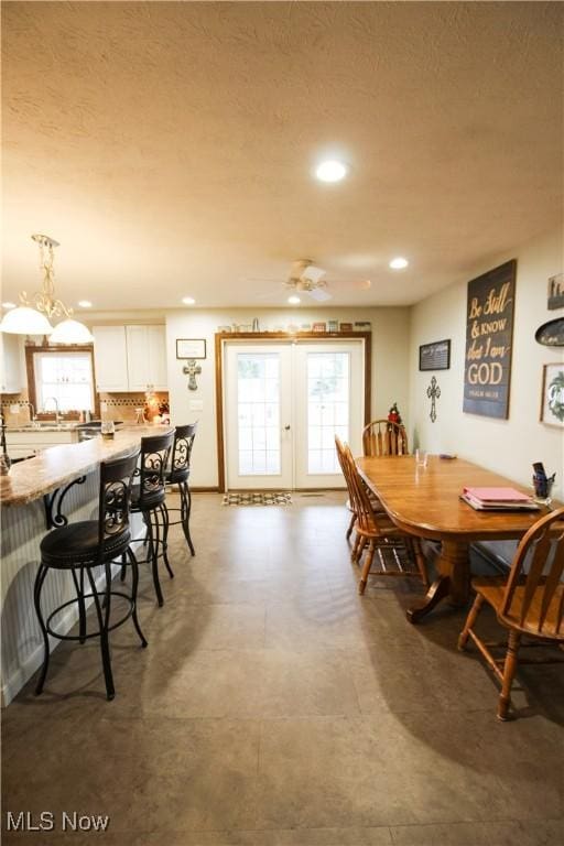 dining space with french doors, a textured ceiling, and sink