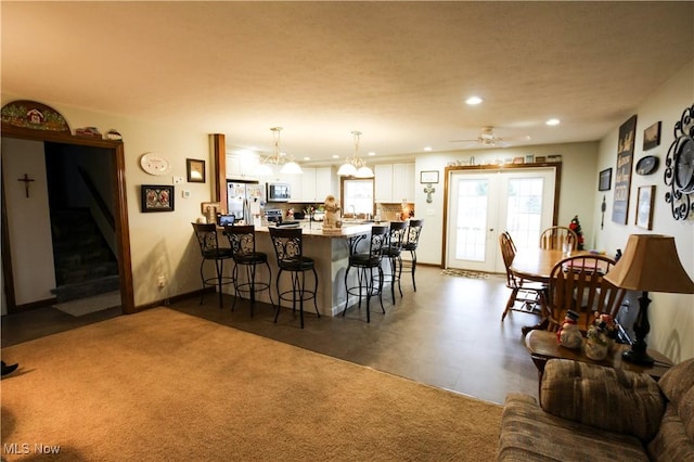 kitchen featuring kitchen peninsula, appliances with stainless steel finishes, a breakfast bar, white cabinets, and hanging light fixtures