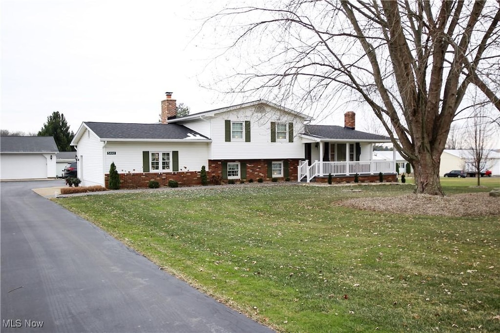 tri-level home with an outdoor structure, covered porch, a front yard, and a garage