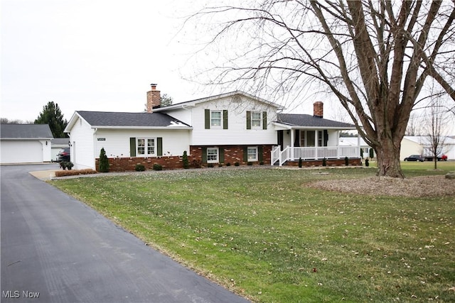 tri-level home with an outdoor structure, covered porch, a front yard, and a garage