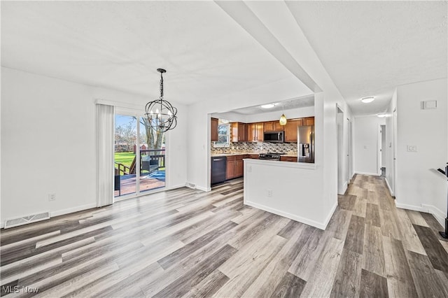 kitchen with light hardwood / wood-style flooring, a notable chandelier, backsplash, decorative light fixtures, and black appliances