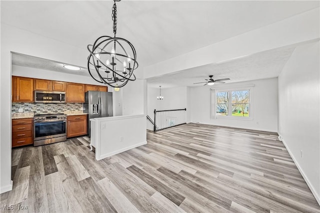 kitchen featuring light hardwood / wood-style floors, decorative light fixtures, decorative backsplash, ceiling fan with notable chandelier, and appliances with stainless steel finishes