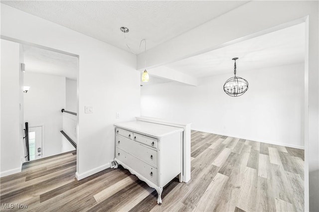 hall with a textured ceiling, light hardwood / wood-style flooring, and a notable chandelier