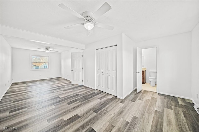 unfurnished bedroom with a closet, hardwood / wood-style flooring, ceiling fan, and ensuite bathroom