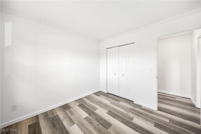 unfurnished bedroom with hardwood / wood-style flooring, ornamental molding, and a closet