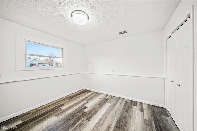 unfurnished room with a textured ceiling and hardwood / wood-style flooring