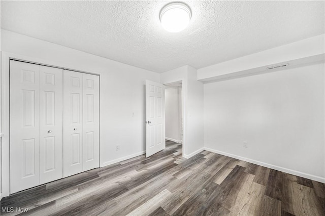 unfurnished bedroom with a closet, wood-type flooring, and a textured ceiling