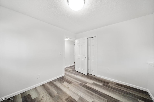 spare room with a textured ceiling and light wood-type flooring