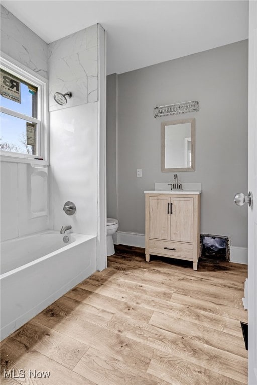 full bathroom with hardwood / wood-style flooring, vanity, toilet, and tiled shower / bath