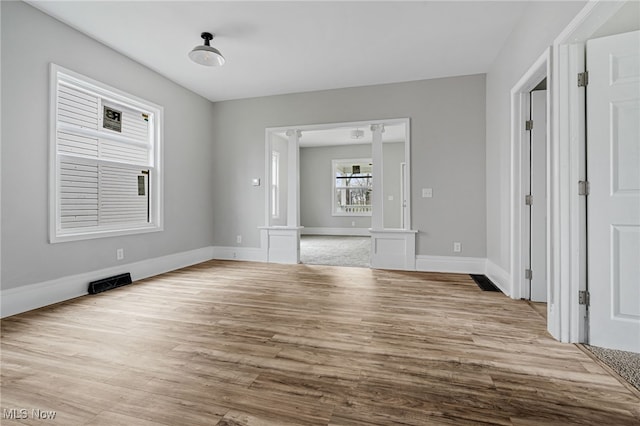 unfurnished living room with decorative columns and light hardwood / wood-style flooring