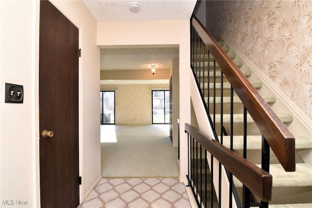 staircase featuring carpet floors and a textured ceiling