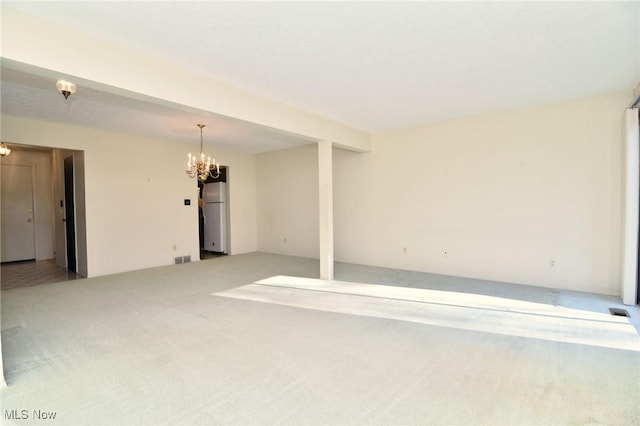 spare room featuring carpet floors and an inviting chandelier