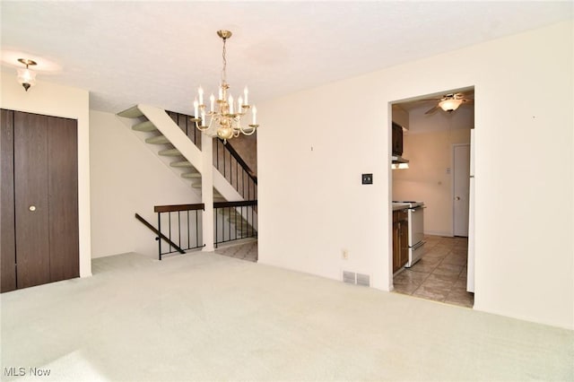 carpeted empty room featuring ceiling fan with notable chandelier