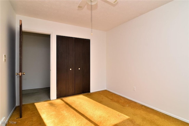 unfurnished bedroom with ceiling fan, carpet floors, a textured ceiling, and a closet