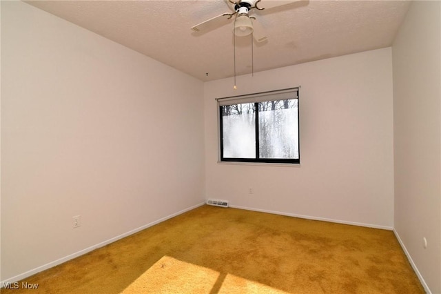 carpeted empty room with ceiling fan and a textured ceiling