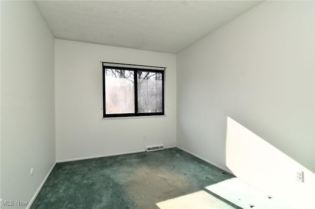 unfurnished room with dark colored carpet and a textured ceiling