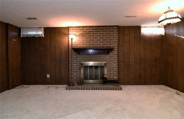 unfurnished living room with a textured ceiling, carpet floors, a brick fireplace, and wooden walls