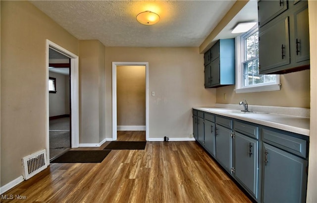 kitchen with a textured ceiling, sink, and dark wood-type flooring