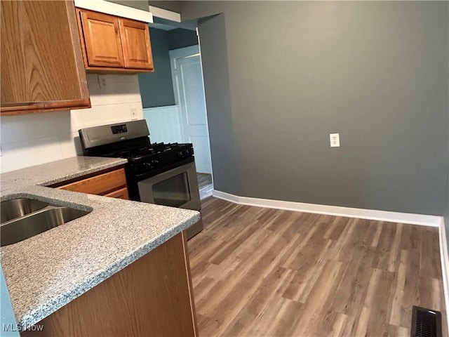 kitchen with light stone counters, dark wood-type flooring, and gas stove