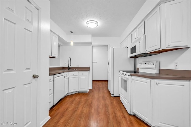 kitchen featuring decorative light fixtures, sink, white appliances, white cabinetry, and a textured ceiling