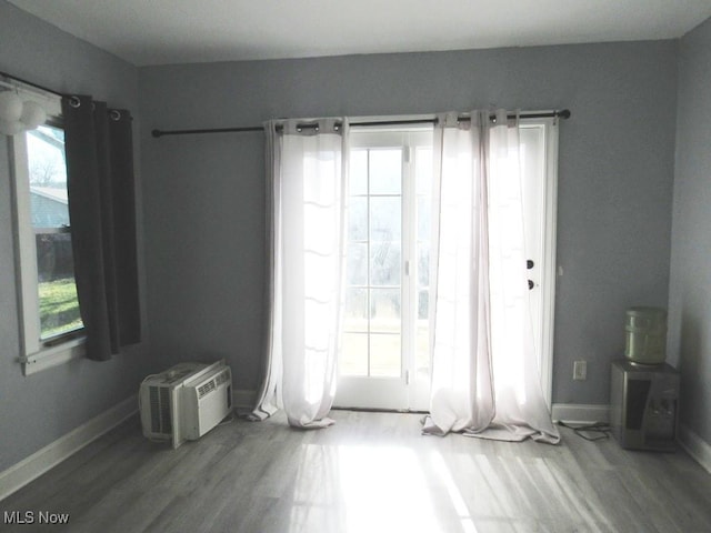 spare room with wood-type flooring, a wall unit AC, and a healthy amount of sunlight