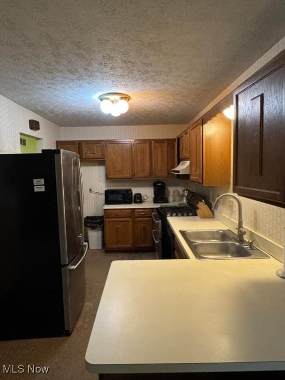 kitchen with sink, a textured ceiling, and appliances with stainless steel finishes