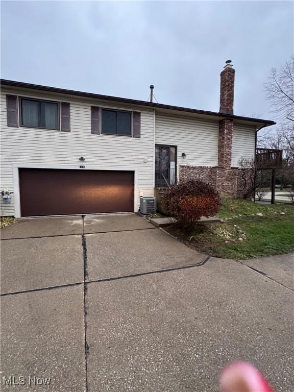 split foyer home featuring a garage and central air condition unit