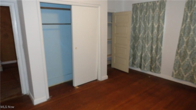 unfurnished bedroom featuring a closet and dark wood-type flooring