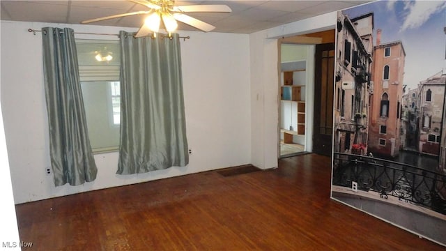 spare room with dark hardwood / wood-style flooring, a drop ceiling, and ceiling fan