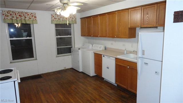 kitchen with a paneled ceiling, white appliances, sink, washer and dryer, and dark hardwood / wood-style floors