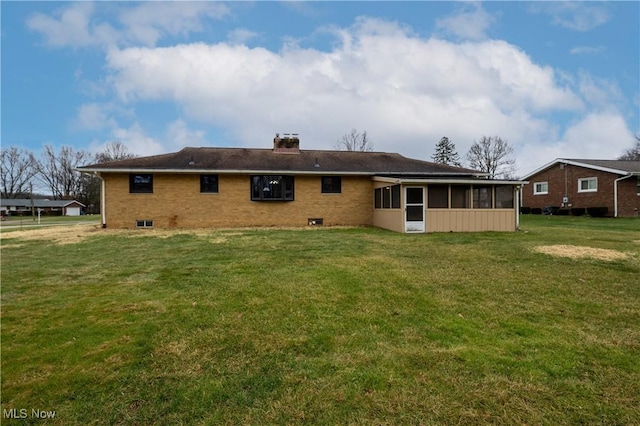 rear view of house featuring a yard and a sunroom