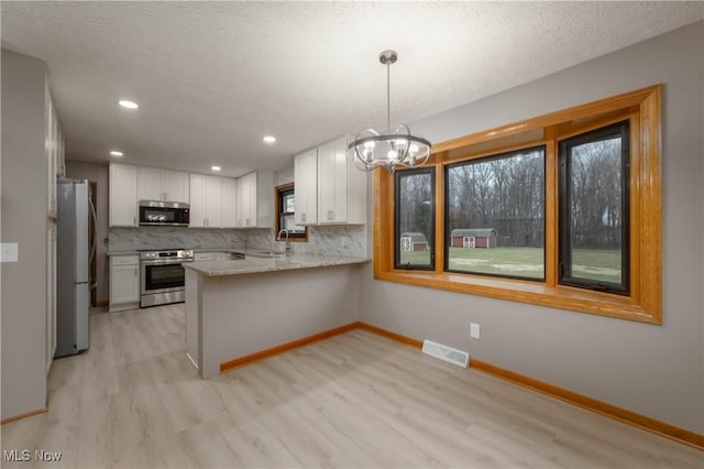 kitchen featuring kitchen peninsula, white cabinetry, hanging light fixtures, and appliances with stainless steel finishes