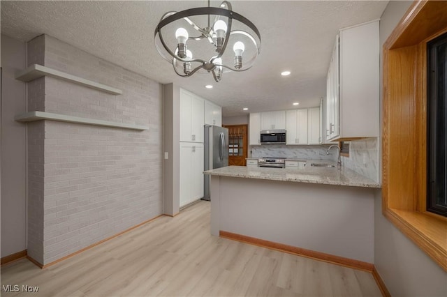 kitchen featuring kitchen peninsula, a textured ceiling, stainless steel appliances, light hardwood / wood-style floors, and white cabinetry